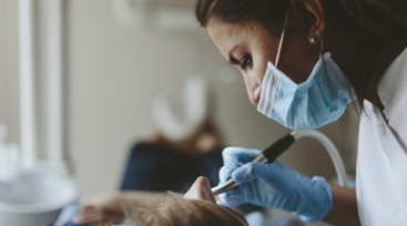 Tandsköterska som undersöker patients tänder.