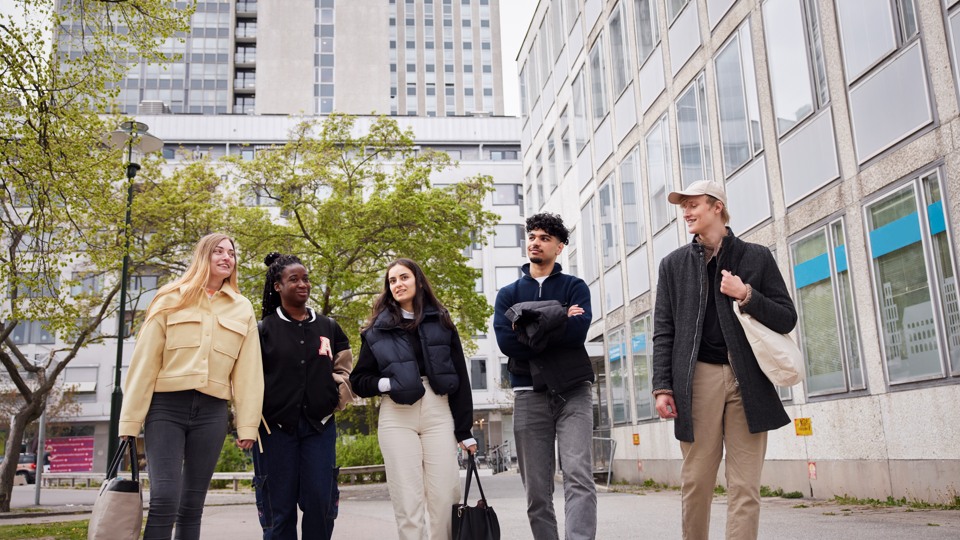 Fem ungdomar promenerar i stadsmiljö