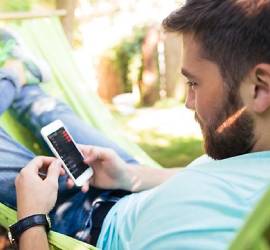 Kvinna sitter på kafé och tittar på sin mobiltelefon