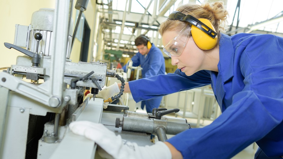 Kvinnlig industriarbetare jobbar vid en metallborr