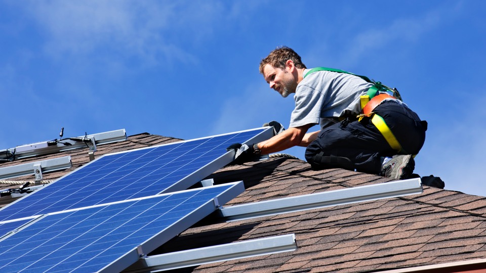Person som monterar solceller på ett tak