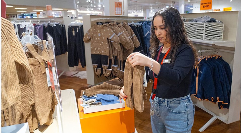 Frishta Yasiri som fått jobb på Åhléns efter en praktik viker kläder.